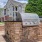 a brick wall with a toilet on it and a house in the background